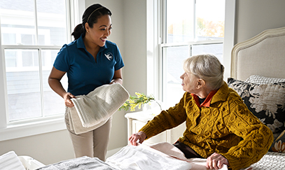 A Visiting Angels caregiver gently guiding an elderly woman with dementia, showcasing compassionate support and understanding in home care.