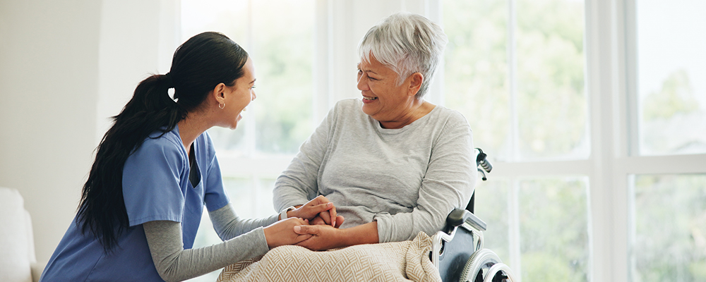 A Visiting Angels caregiver providing comforting support to an elderly patient in a peaceful home environment, highlighting the essence of palliative care.