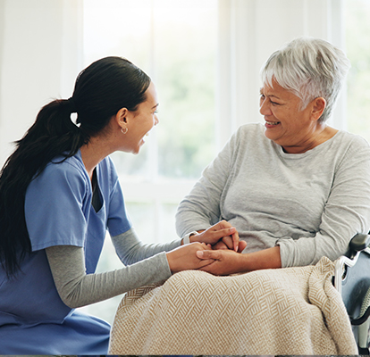 A Visiting Angels caregiver providing comforting support to an elderly patient in a peaceful home environment, highlighting the essence of palliative care.