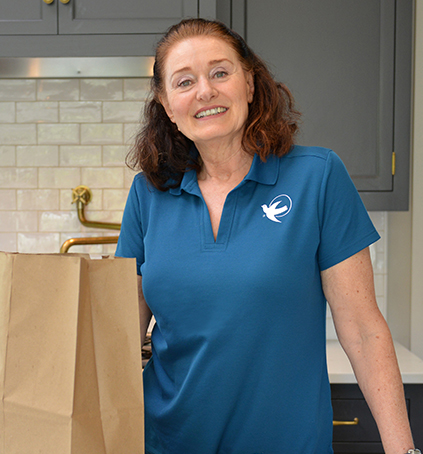 A female Visiting Angels caregiver puts away groceries.